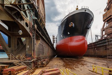 image of large red and black ship offshore on site