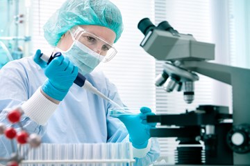 a person carries out laborartory testing and a microscope