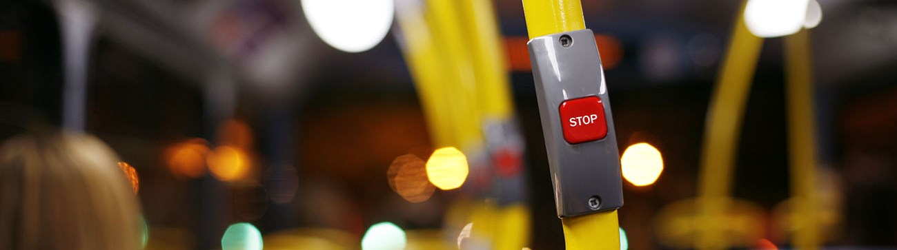 close up of red stop button on yellow pole on a bus