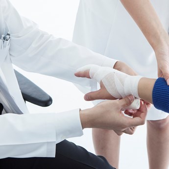 close up of medical bandage being wrapped around a hand and wrist