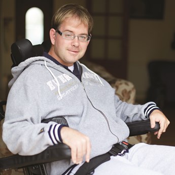 image of a man, wearing a grey hoody, in a wheelchair