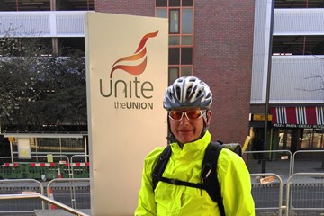 a cyclist in hi-vis gear and a helmet stands next to his bike