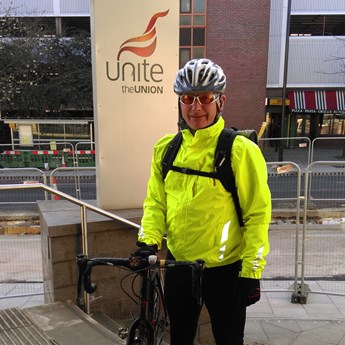 a cyclist in hi-vis gear and a helmet stands next to his bike