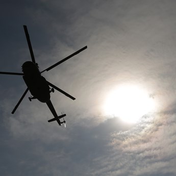 ground level view of helicopter and sun breaking through the clouds