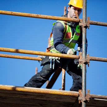 construction worker wearing high vis working on scaffolding
