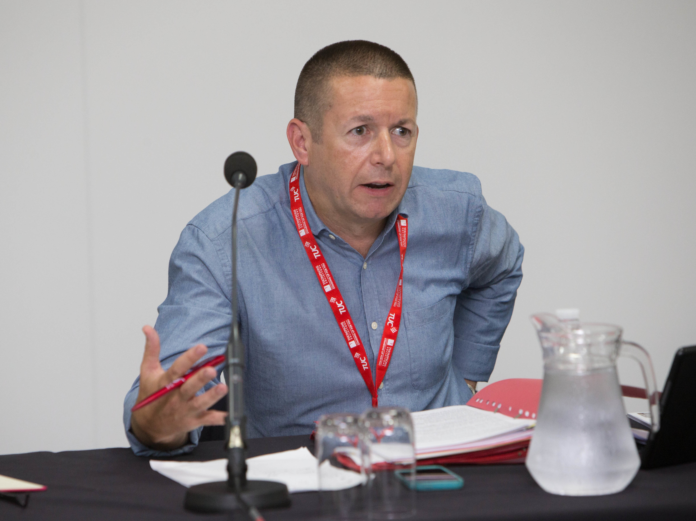 Howard Beckett sat at a desk talking with a microphone