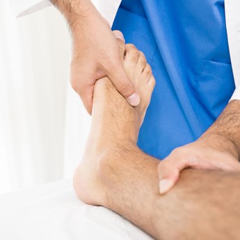 close up of leg being examined with one hand on the foot and one hand on the shin
