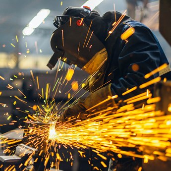 bright orange electric sparks with workman in protective clothing in background