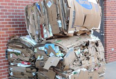 three compact cardboard parcels stacked against a red brick wall