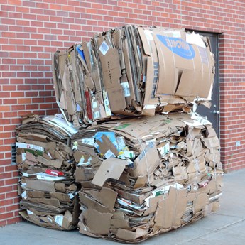 three compact cardboard parcels stacked against a red brick wall